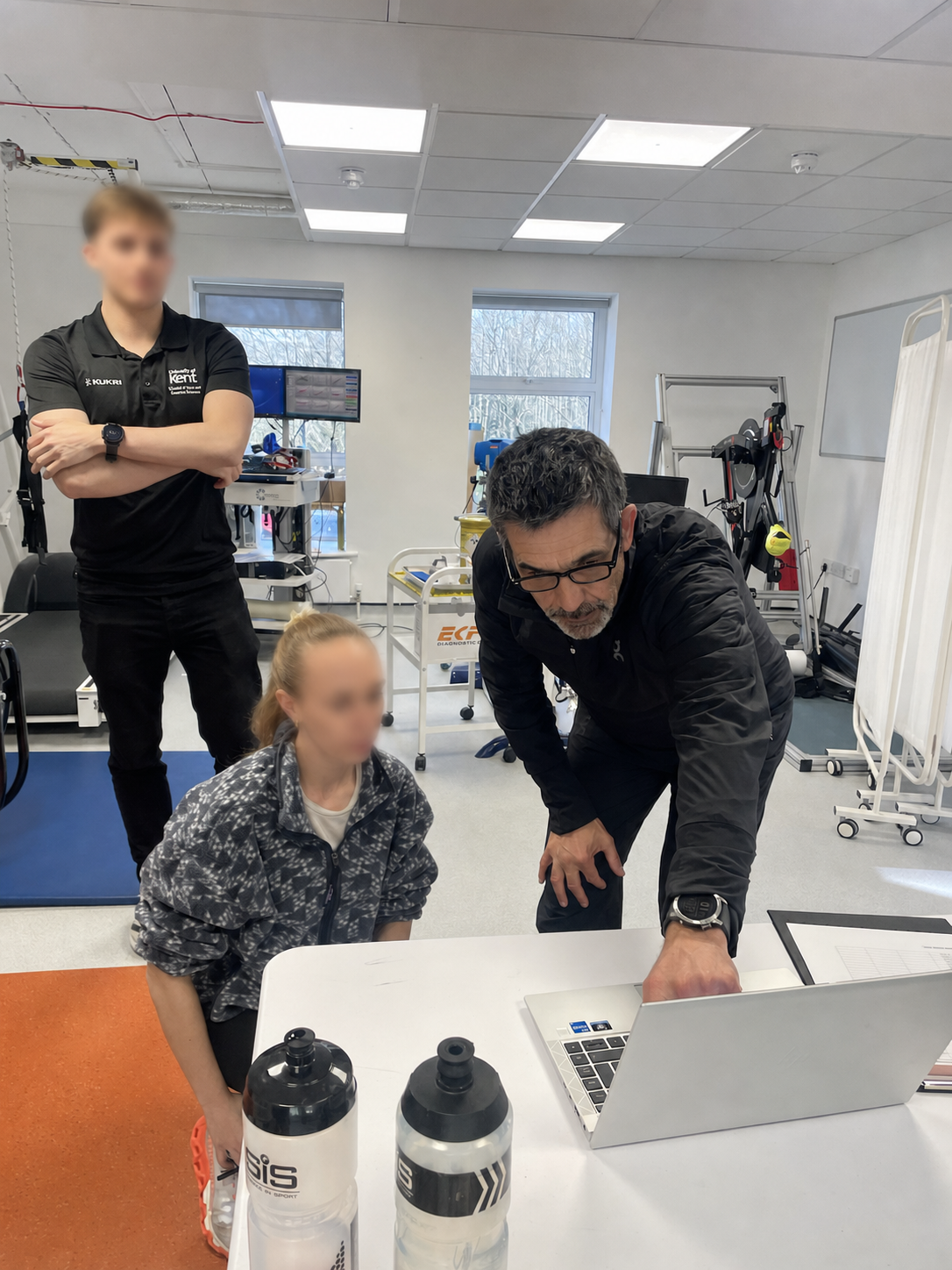 Neil Danby reviewing performance data with an athlete and a sports scientist in a university laboratory